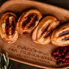 Cztery grillowane oscypki z żurawiną i rozmarynem na drewnianej desce.