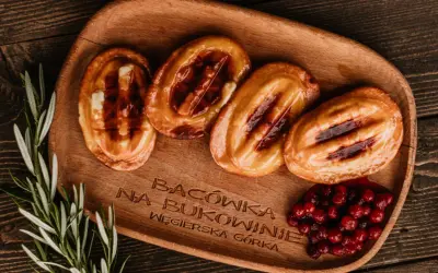 Cztery grillowane oscypki z żurawiną i rozmarynem na drewnianej desce.
